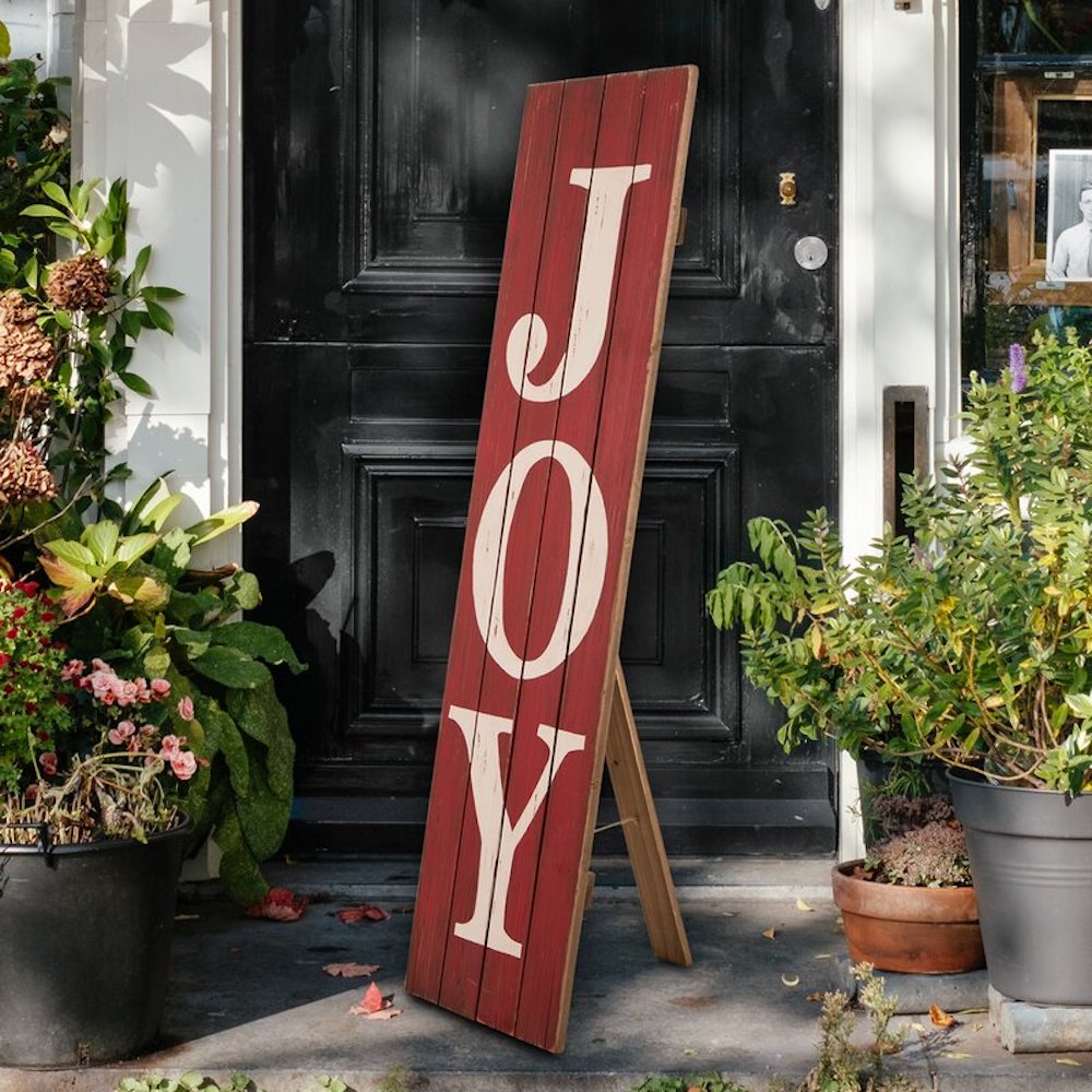 Tall red and white wooden sign with the word “joy” painted on the front