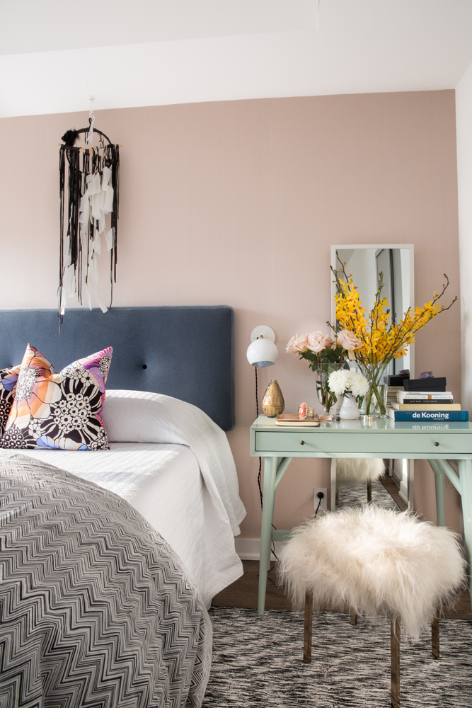 pink bedroom with side table, stool and dreamcatcher