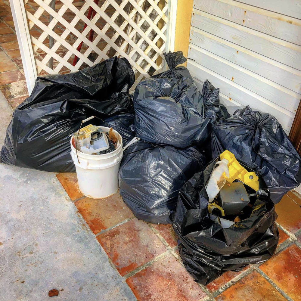 Bags of garbage sit on a clay tile patio