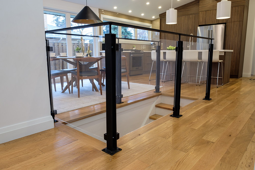 Wood floors and a staircase with black and clear glass railings