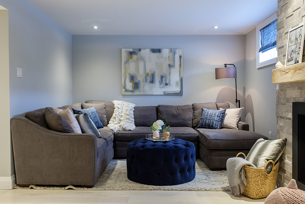 Stylish family room with a royal blue ottoman, brown couch sectional and blue walls