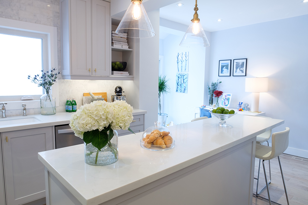 A large white kitchen island with croissants and a vase full of white hydrangeas