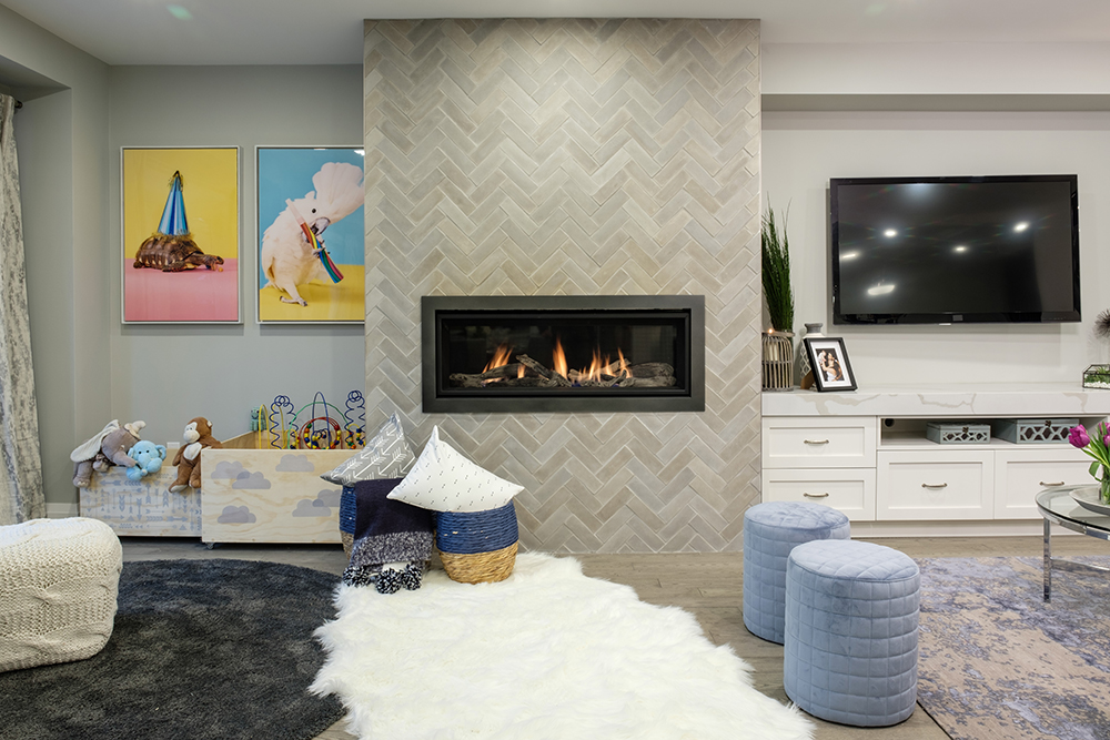 A chic modern living area features a long gas fireplace, children's play area and a large TV