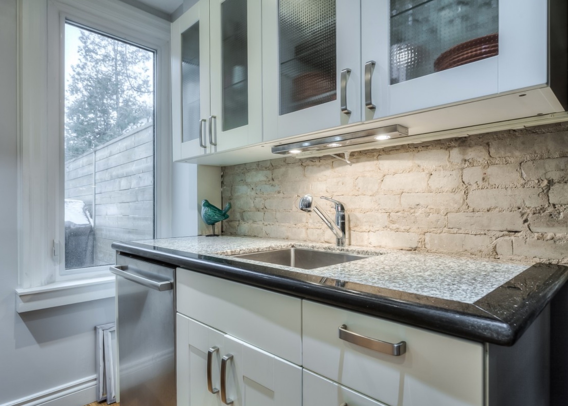 The granite countertop surrounds the sink, with the stainless steel dishwasher located beneath