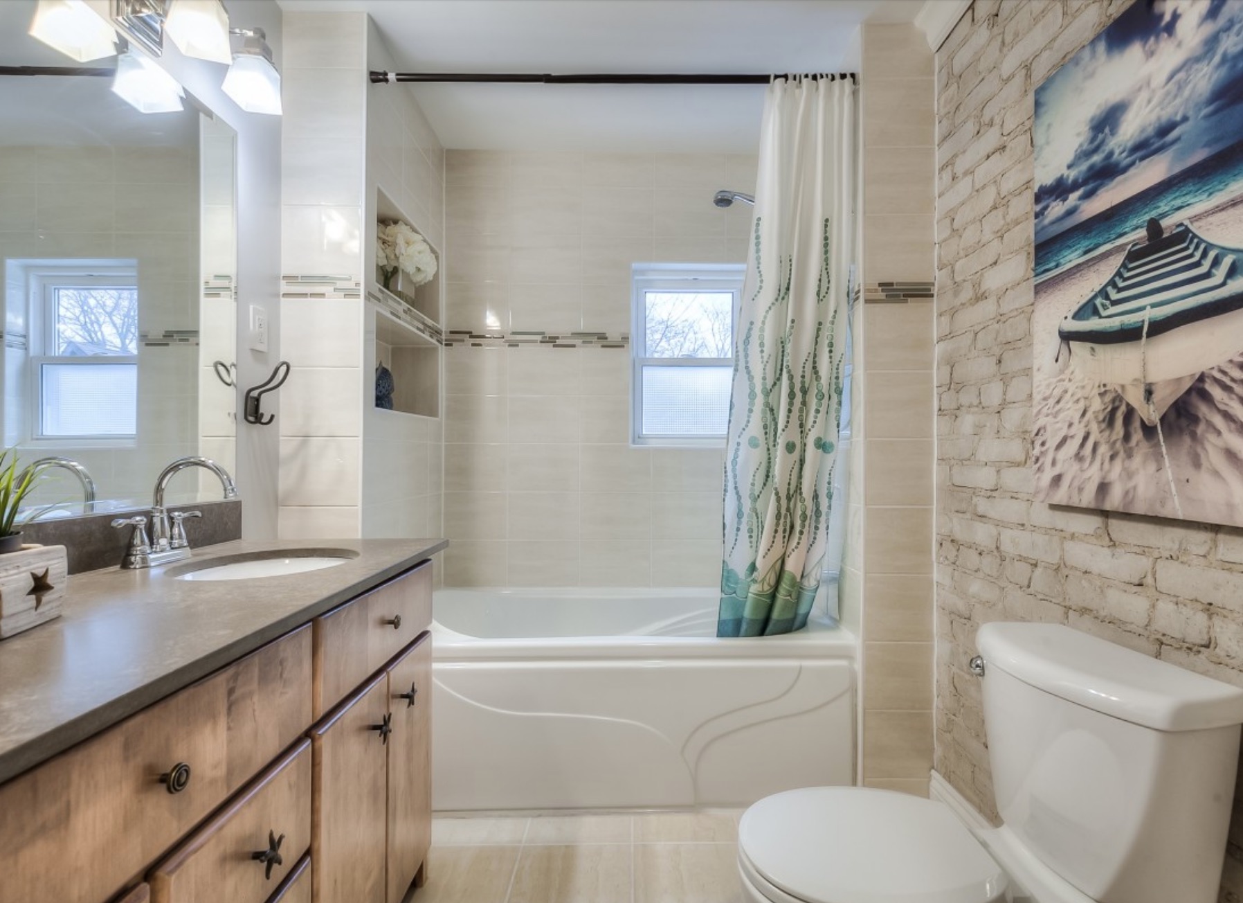The only bathroom in the house is fully renovated with exposed brick and wood cabinet-style vanity