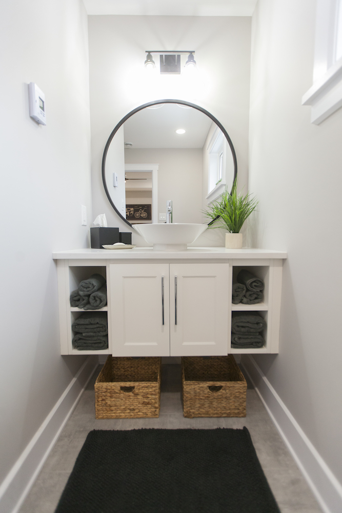 White floating bathroom vanity with bowl sink and round mirror