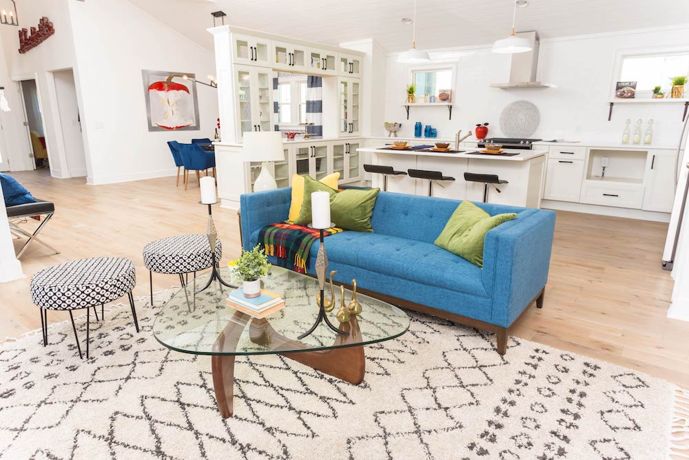 Masters of Flip primary colour renovation living room with blue couch, glass-topped coffee table and white kilim rug