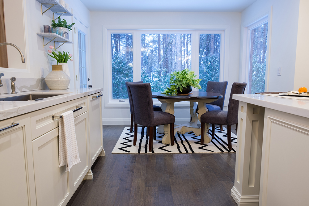 Breakfast nook in a modern white kitchen with dark wood floors and lots of windows