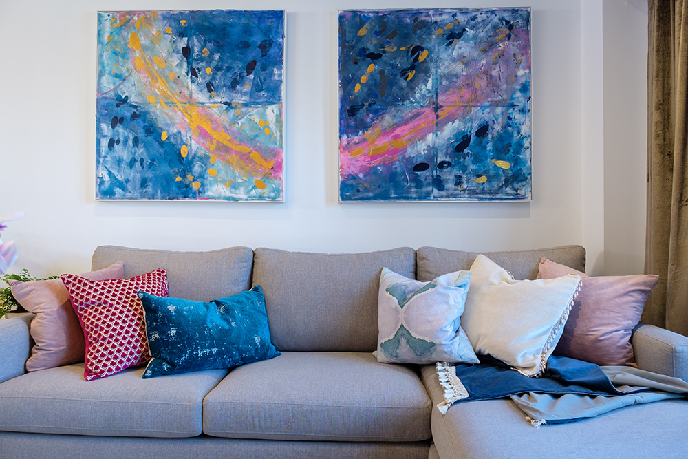 Modern living room with a grey couch covered in colourful throw pillows and bold artwork on the wall
