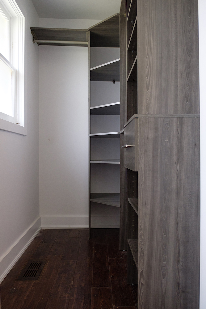 Modern walk in closet with dark wood floors and grey stained wood built ins