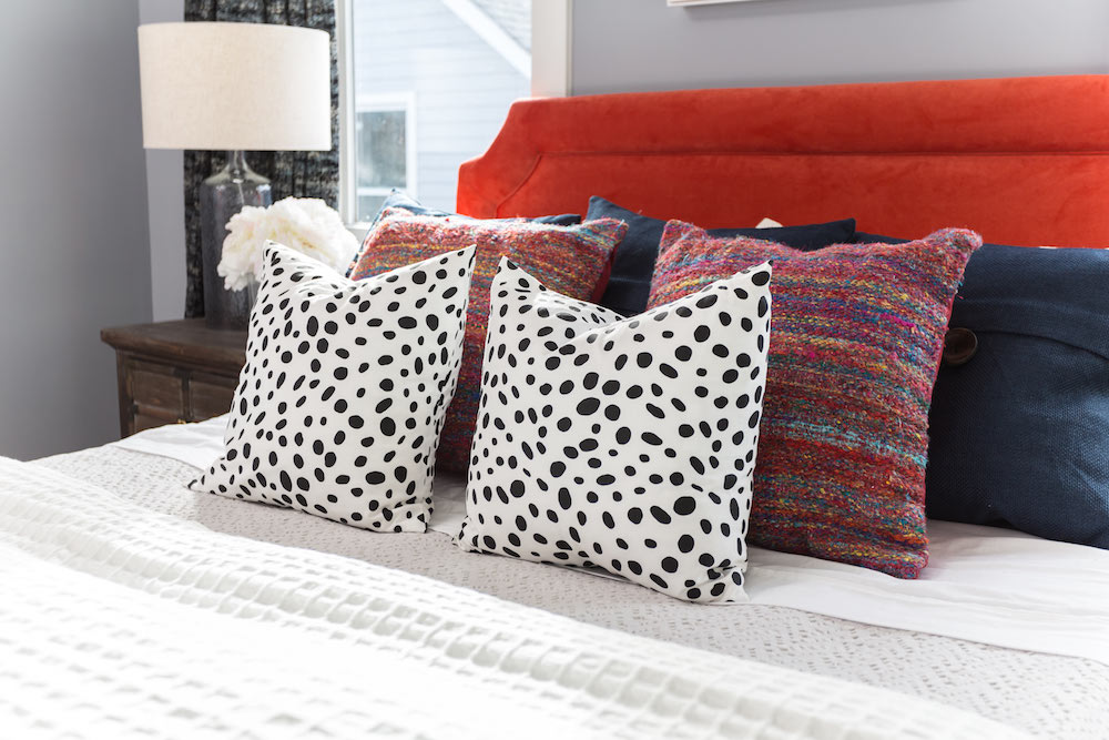 Masters of Flip train station house bedroom with red headboard, grey walls and black and white spotted throw pillows
