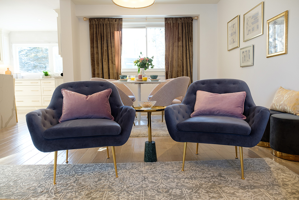 Modern living room with two purple armchairs, bronze drapes and a breakfast table in behind