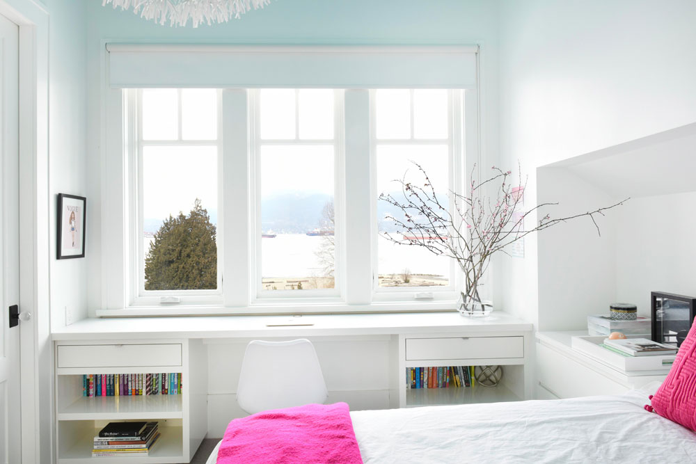 three windows in white bedroom with hot pink cushion, throw and branch arrangement
