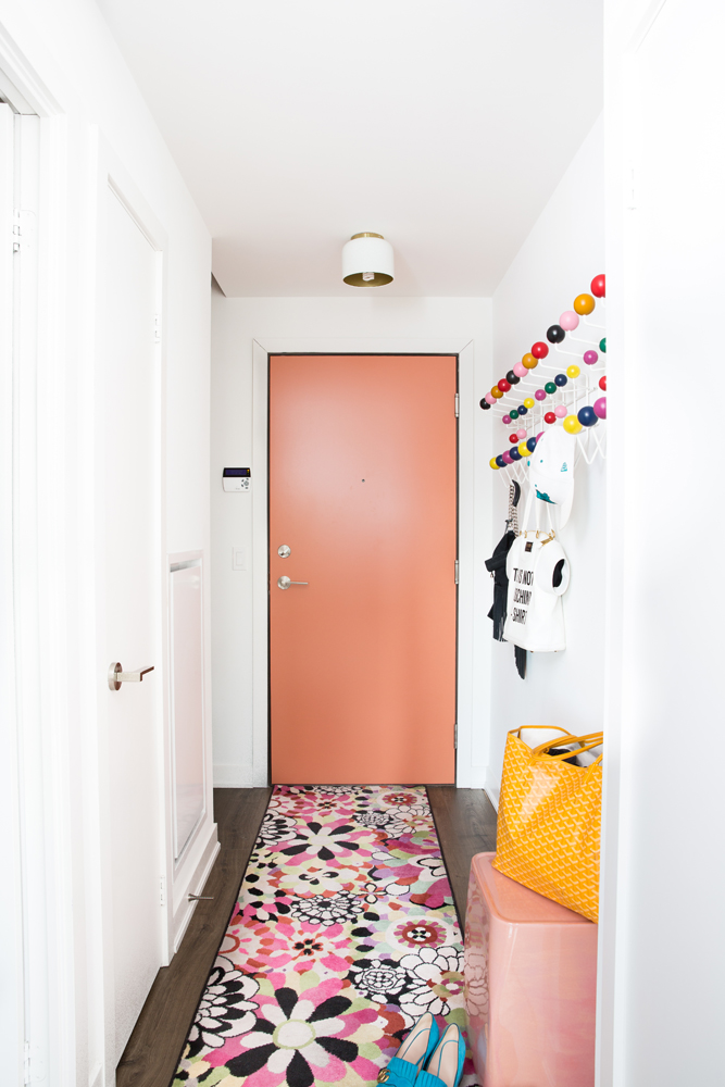 Front hallway with pink door and floral carpet