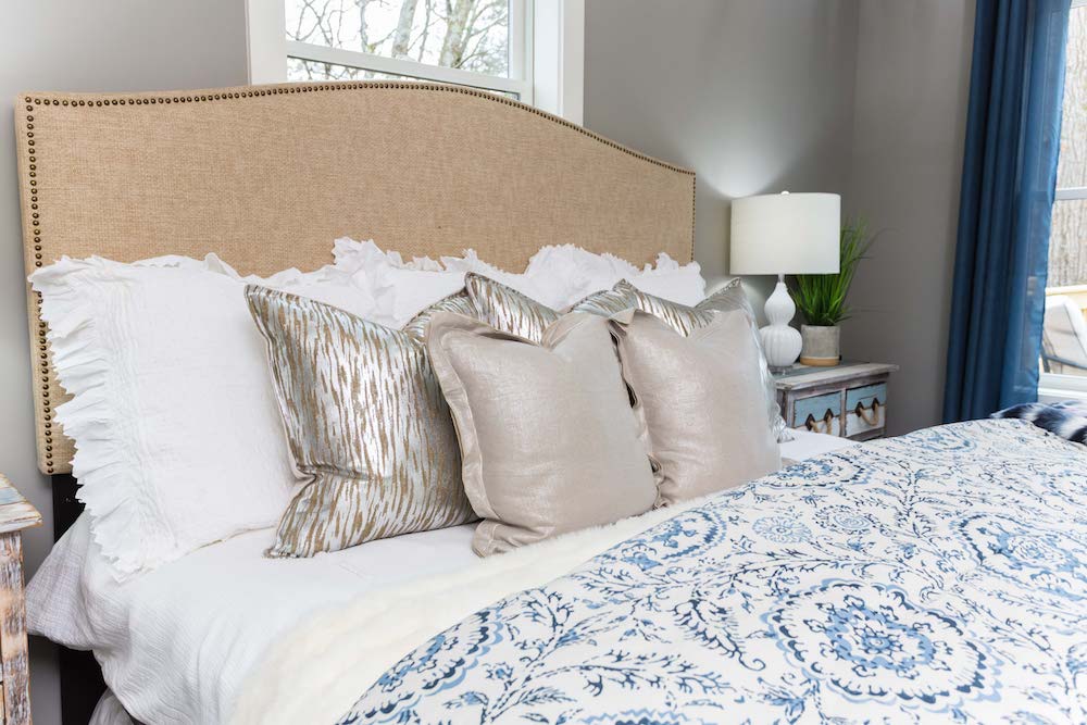Masters of Flip split level master bedroom bed piled with blue and white quilts, white pillows and gold throw pillows