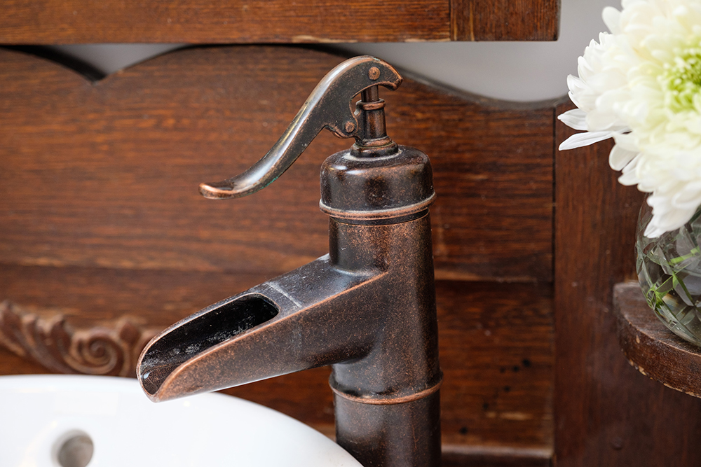 Bathroom sink bronze faucet in the shape of an old farm water pump