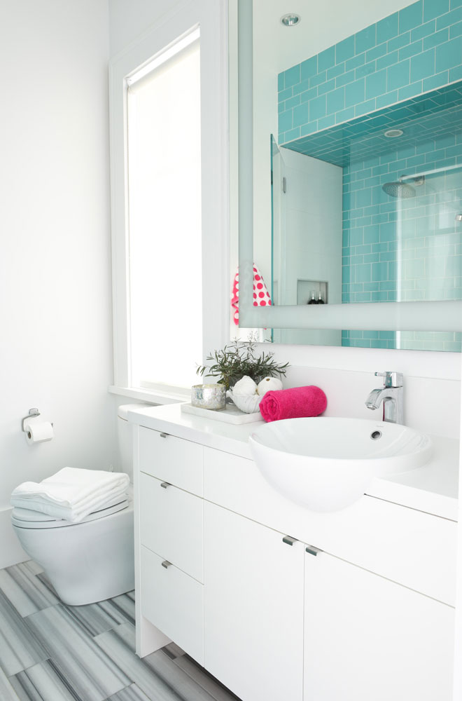white bath with blue tile shower and one hot pink rolled up towel