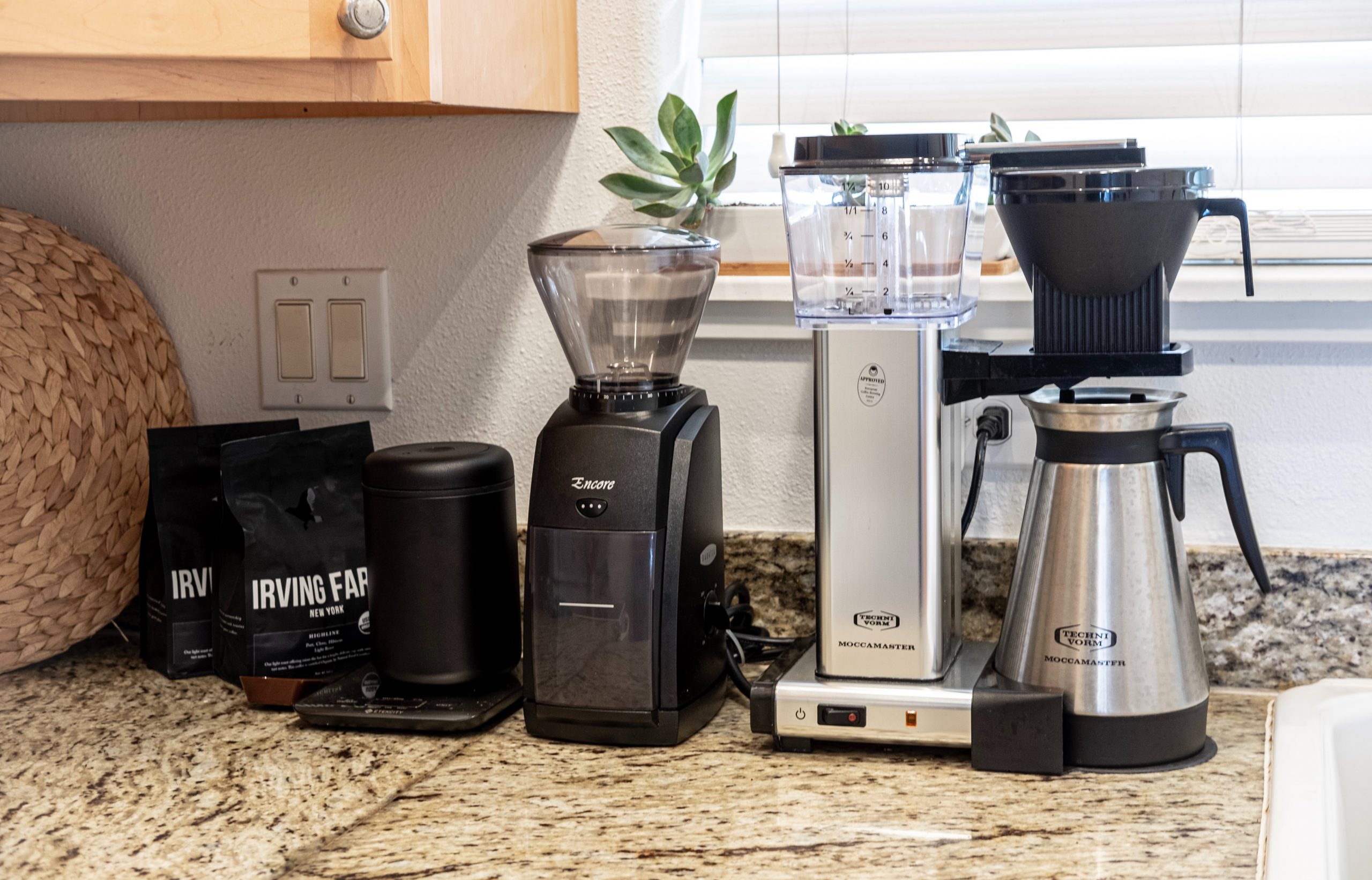 Close up of several small kitchen appliances arranged on a kitchen counter.