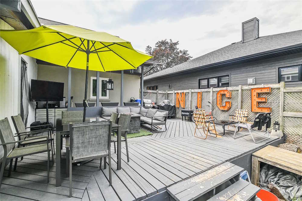 grey deck with grey patio furniture, a lime-green umbrella and orange letters on a fence