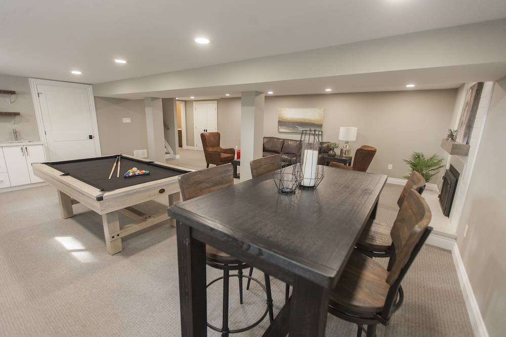 Large basement family room with a pool table, tall dining table, wet bar and brown leather furniture
