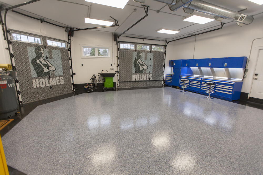 Large garage space with shiny grey floors and two automatic doors stamps with the Holmes logo