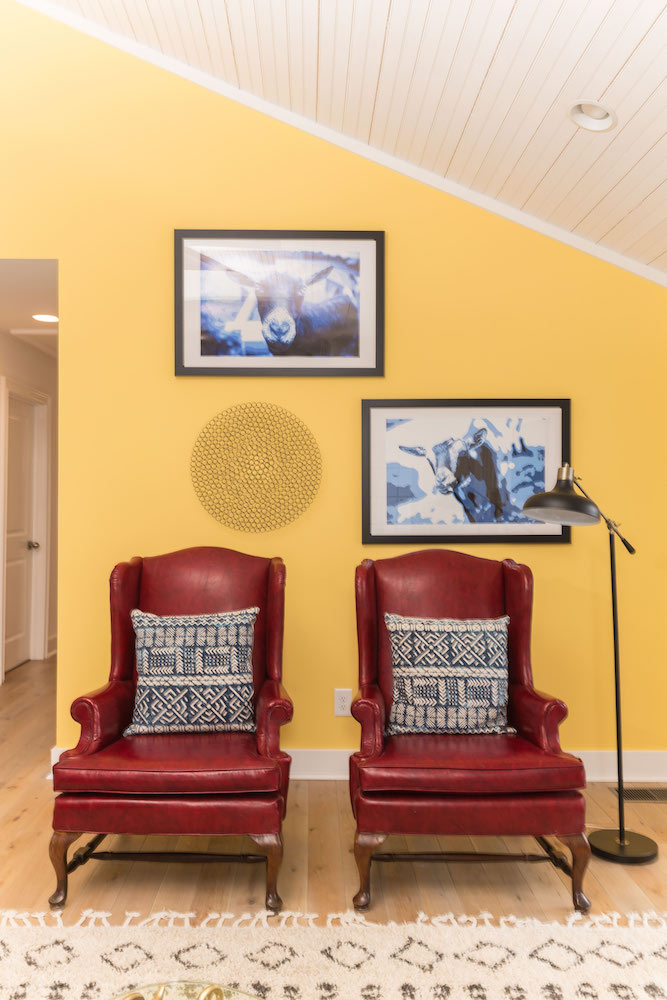 Masters of Flip primary colour renovation living room with red-leather armchairs, yellow wall and blue goat artwork