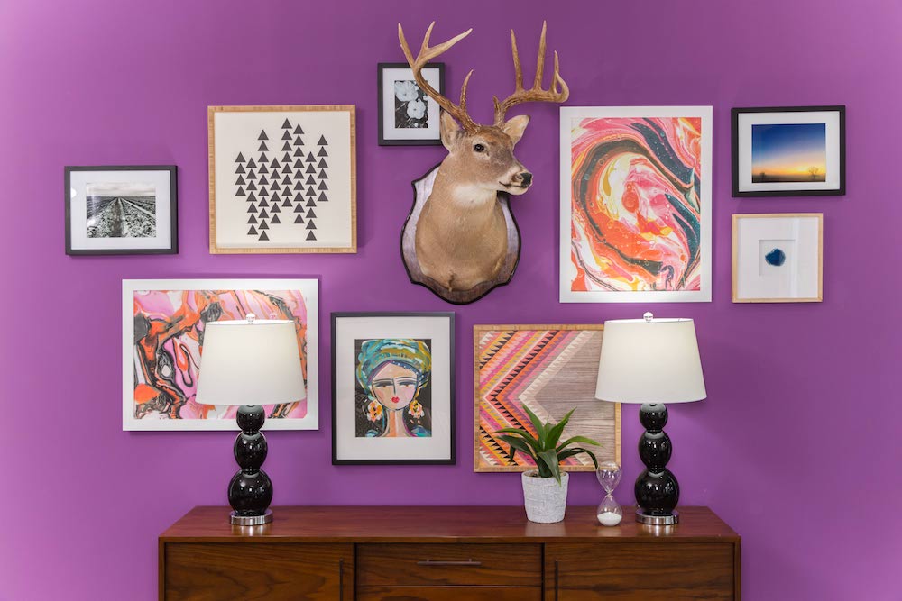 Masters of Flip bohemian Victorian house living room purple feature wall full of artwork and a taxidermy deer head