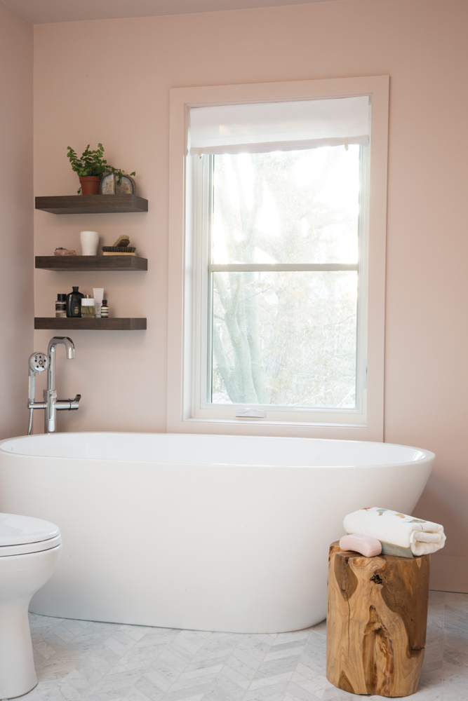 Vessel tub in pink bathroom with wooden stool and floating shelves