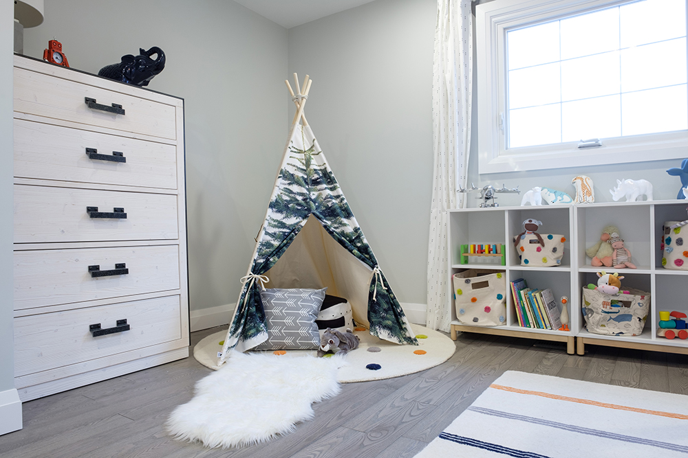 Children's room with a play teepee, white faux sheepskin rug, white dresser and cubbies filled with toys