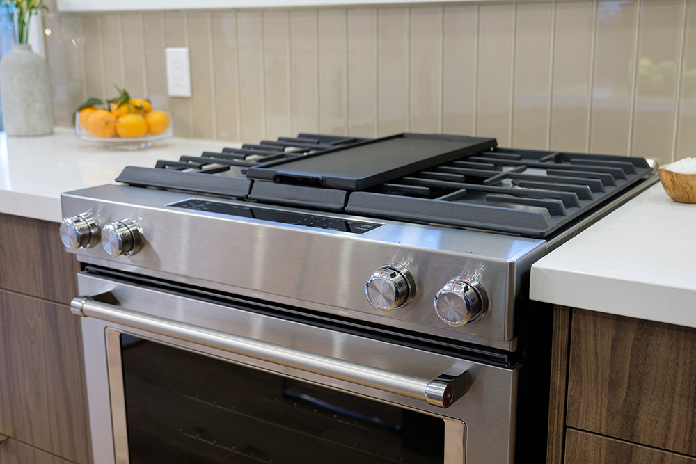 Professional stainless steel gas range with white countertops and wood faced cabinets