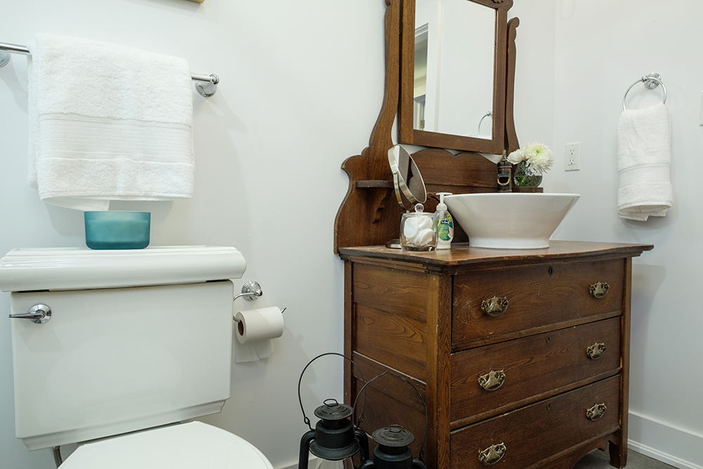 Modern bathroom with a white toilet and a repurposed antique dresser as a vanity and sink
