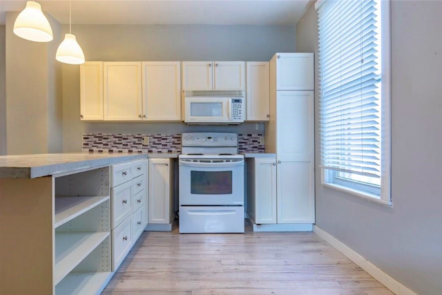 Spacious kitchen in neutral tones with plenty of storage space and tiled backsplash