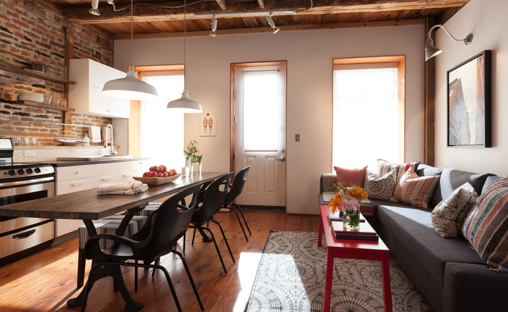 Brick-walled loft with an elegant industrial dining table in kitchen.
