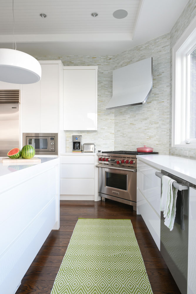 corner of kitchen with green diamond-print runner and white modern range hood