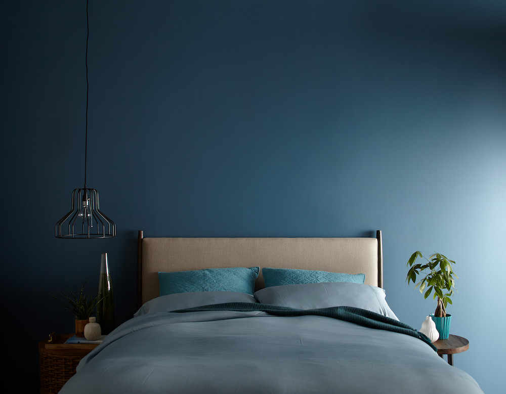Chic bedroom painted in Behr Blueprint S470-5 paint with a bed with a tan headboard and blue bedsheets