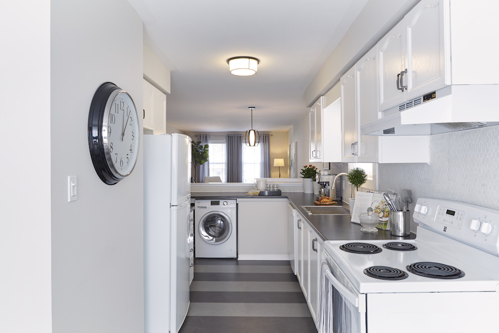 Buyers Bootcamp backwards bungalow kitchen striped floor, white cabinets, black countertops and white appliances