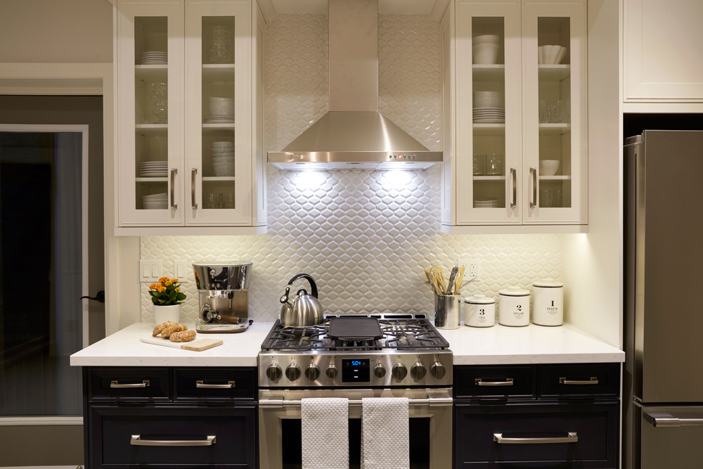 Modern white kitchen with white and black cabinets and textured backsplash.