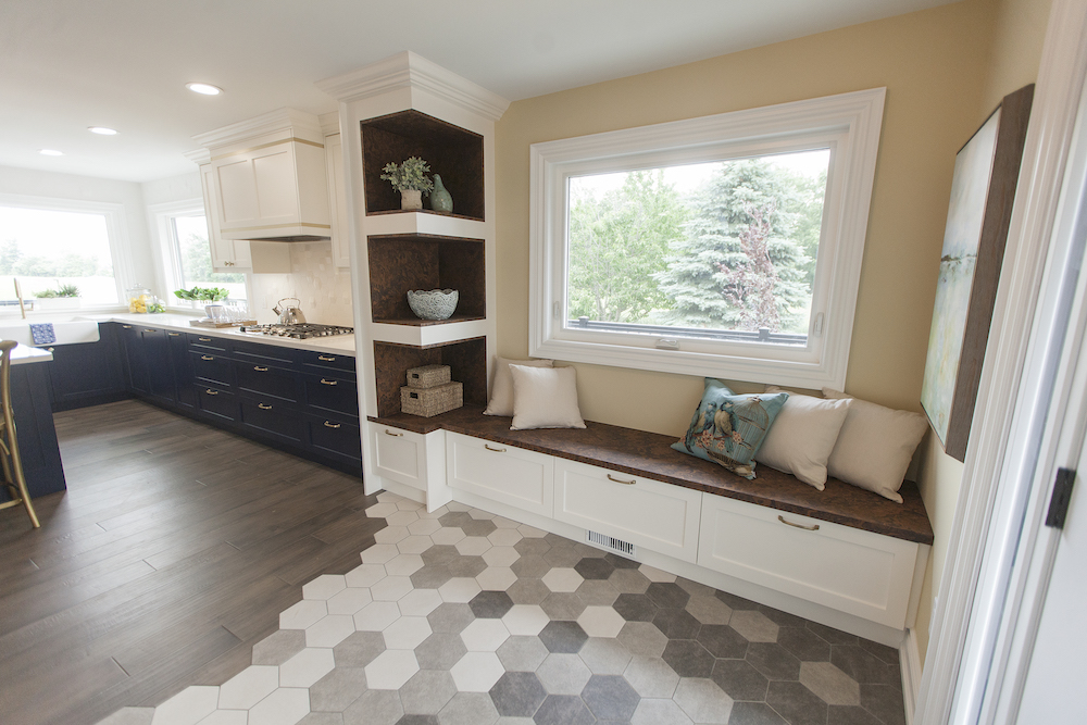 Home entryway with grey and white hexagon tiles, a bench seat and kitchen beyond