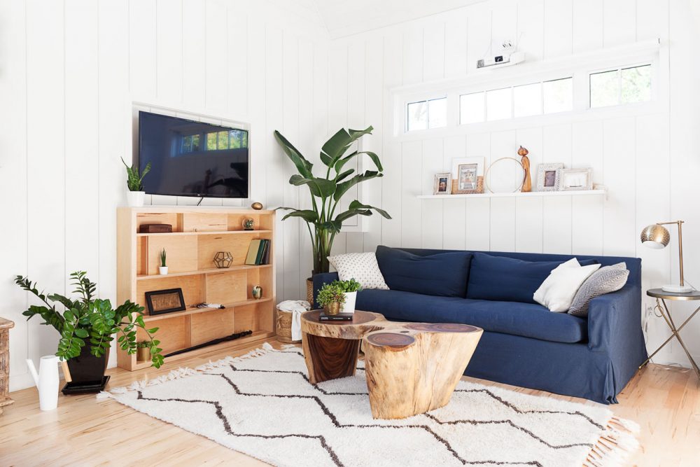 white living room with navy slip covered sofa under window and plant in corner