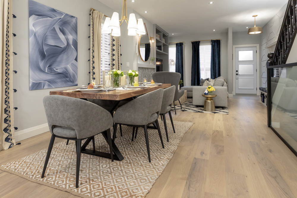 Chic dining table sits in a newly renovated home with light wood floors and a gold chandelier