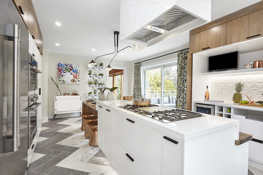 Modern kitchen full of bleached oak cabinets, a huge quartz island and large grey herringbone tile floors