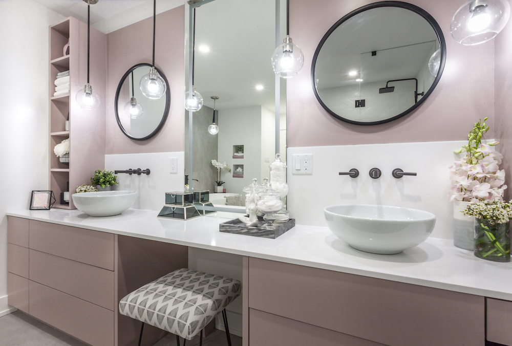 Modern bathroom with pink cabinets, two vessel sinks and two round mirrors