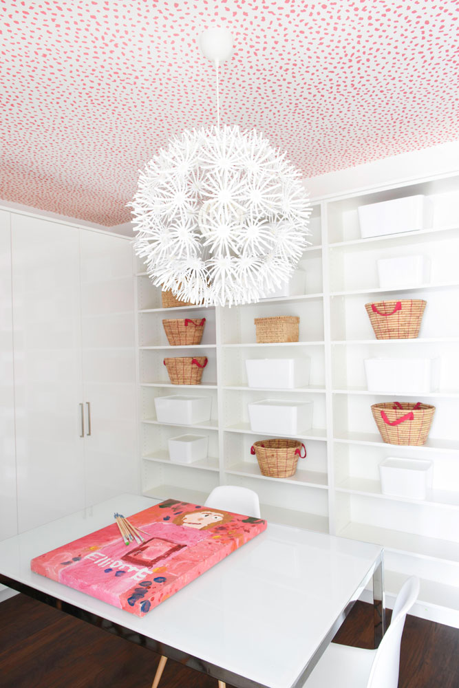craft room with white shelves with baskets and white and pink pattern ceiling