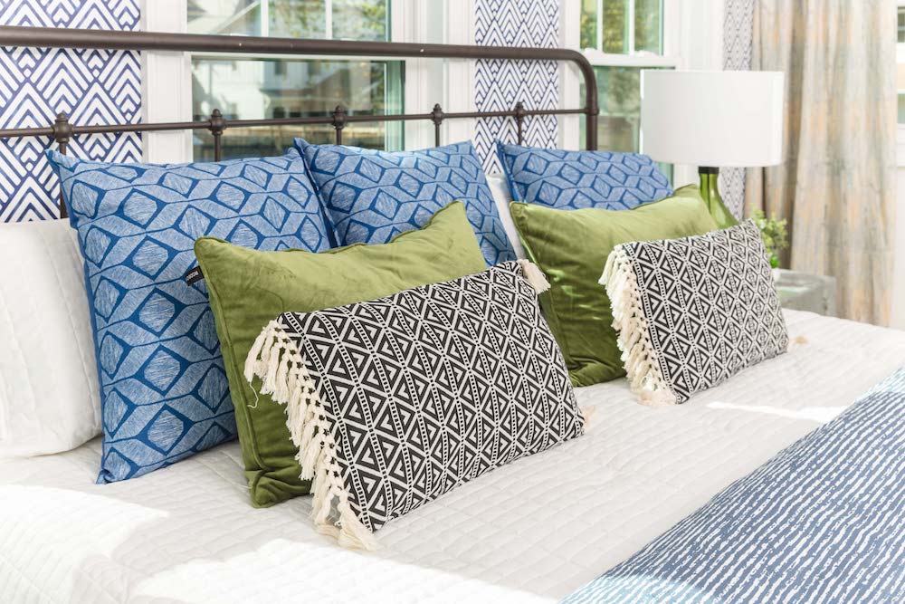 Masters of Flip primary colour renovation master bedroom bed headboard with blue geometric wallpaper and throw pillows