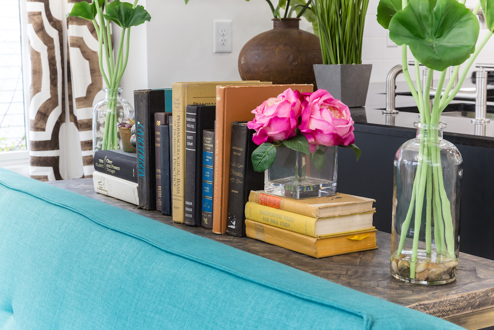 Masters of Flip train station house blue couch with books and flowers displayed on wooden sideboard