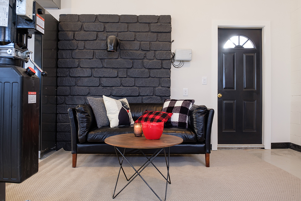 Luxury garage with a black couch against a black brick wall