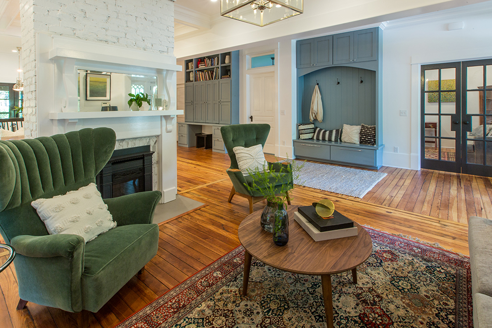 A green and blue living room with a built-in bench as an entryway landing pad for coats and shoes.