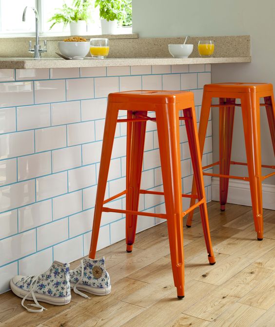 White subway tile island with blue grout and orange stools