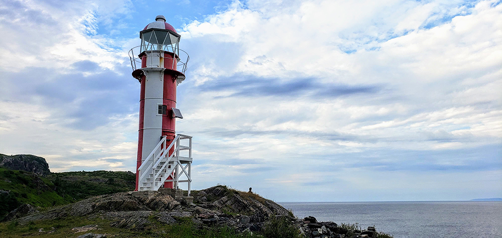 A cast iron lighthouse on the Newfoundland coast with a red and white colour scheme