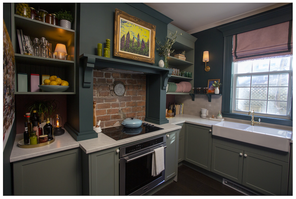 dark green kitchen with brick wall and framed art on wwall